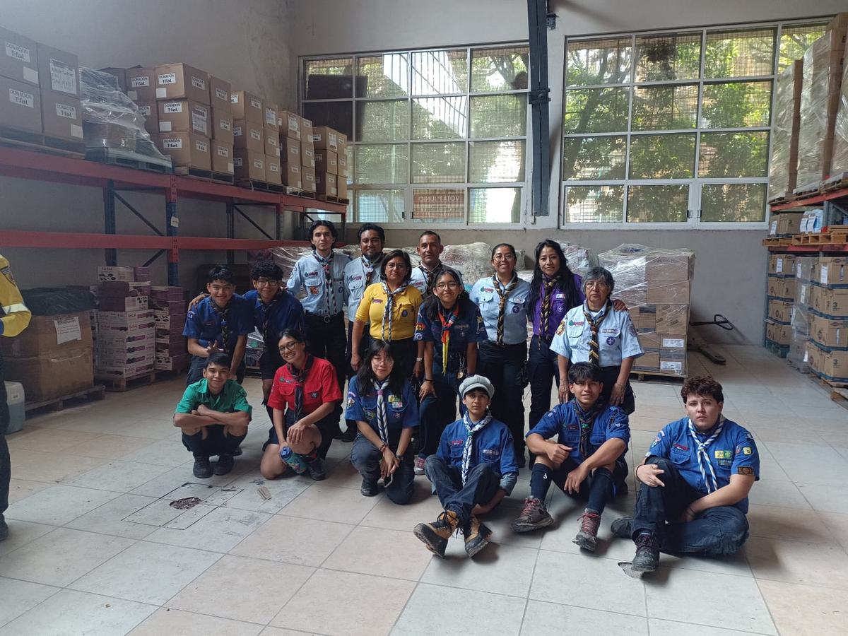 Grupo de voluntarios scouts con uniforme reunidos en una bodega de insumos