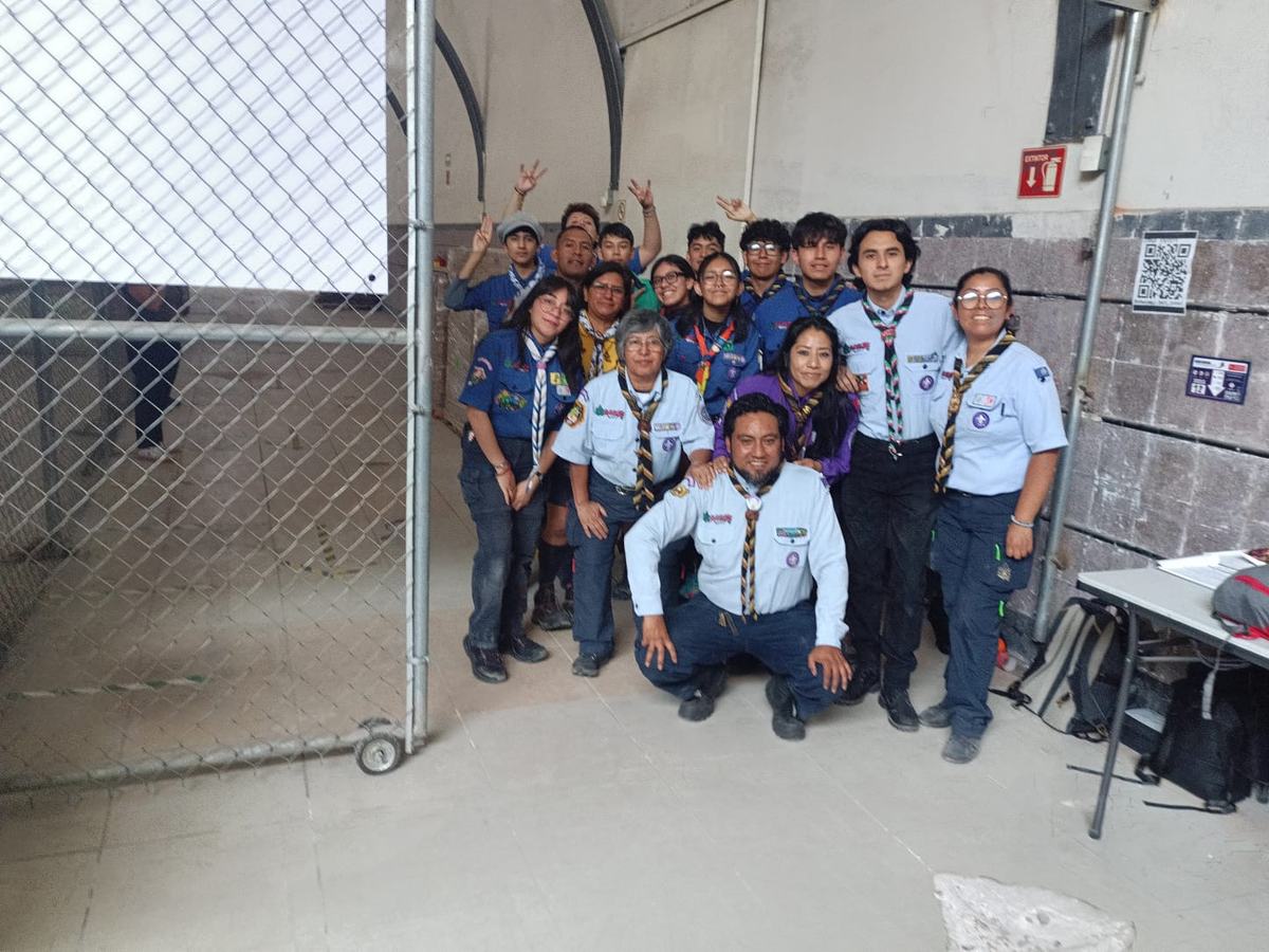 Grupo de scouts con uniforme y pañoleta reunidos en un almacén